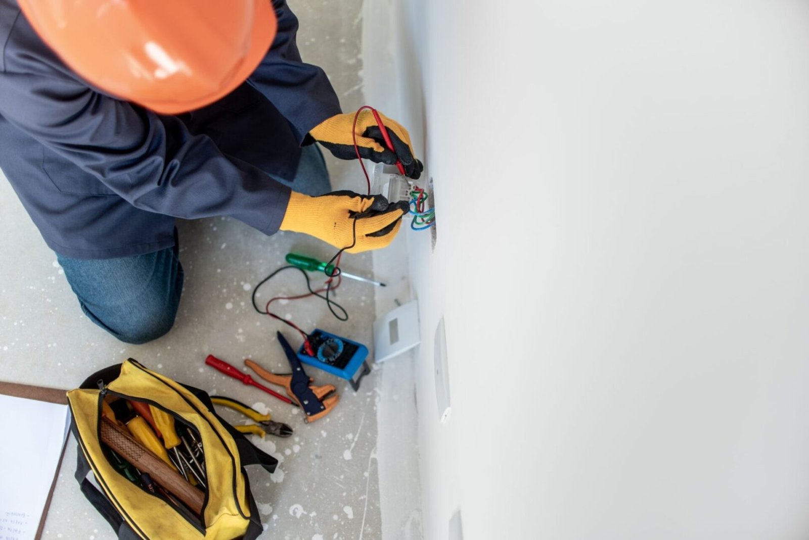 A person in an orange helmet working on wires.