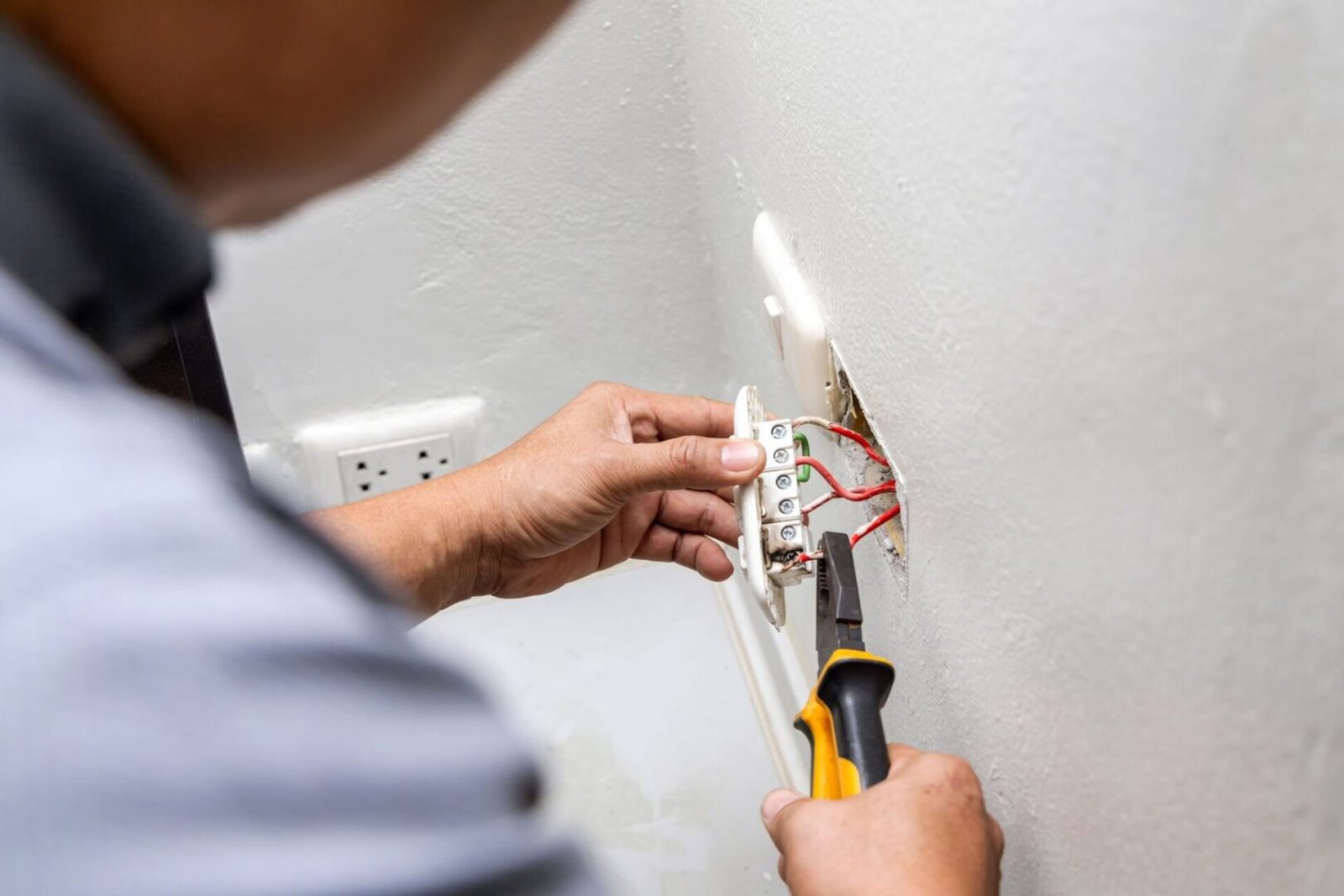 A person with a screwdriver and some electrical wires.