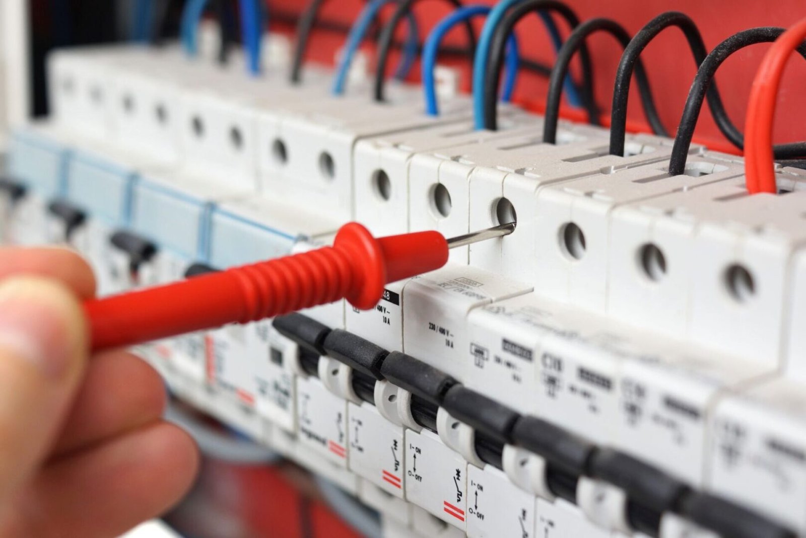 Red multimeter probe testing circuit breakers