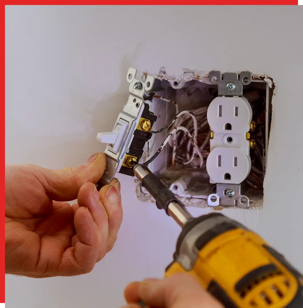 Hands wiring a wall light switch with drill