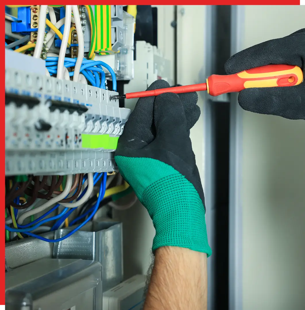 Gloved technician tightening a screw in electrical panel